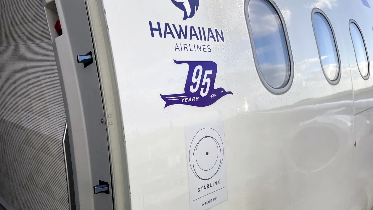Side of a Hawaiian Airlines aircraft, with Starlink Wi-Fi advertised on the side, near the door.
