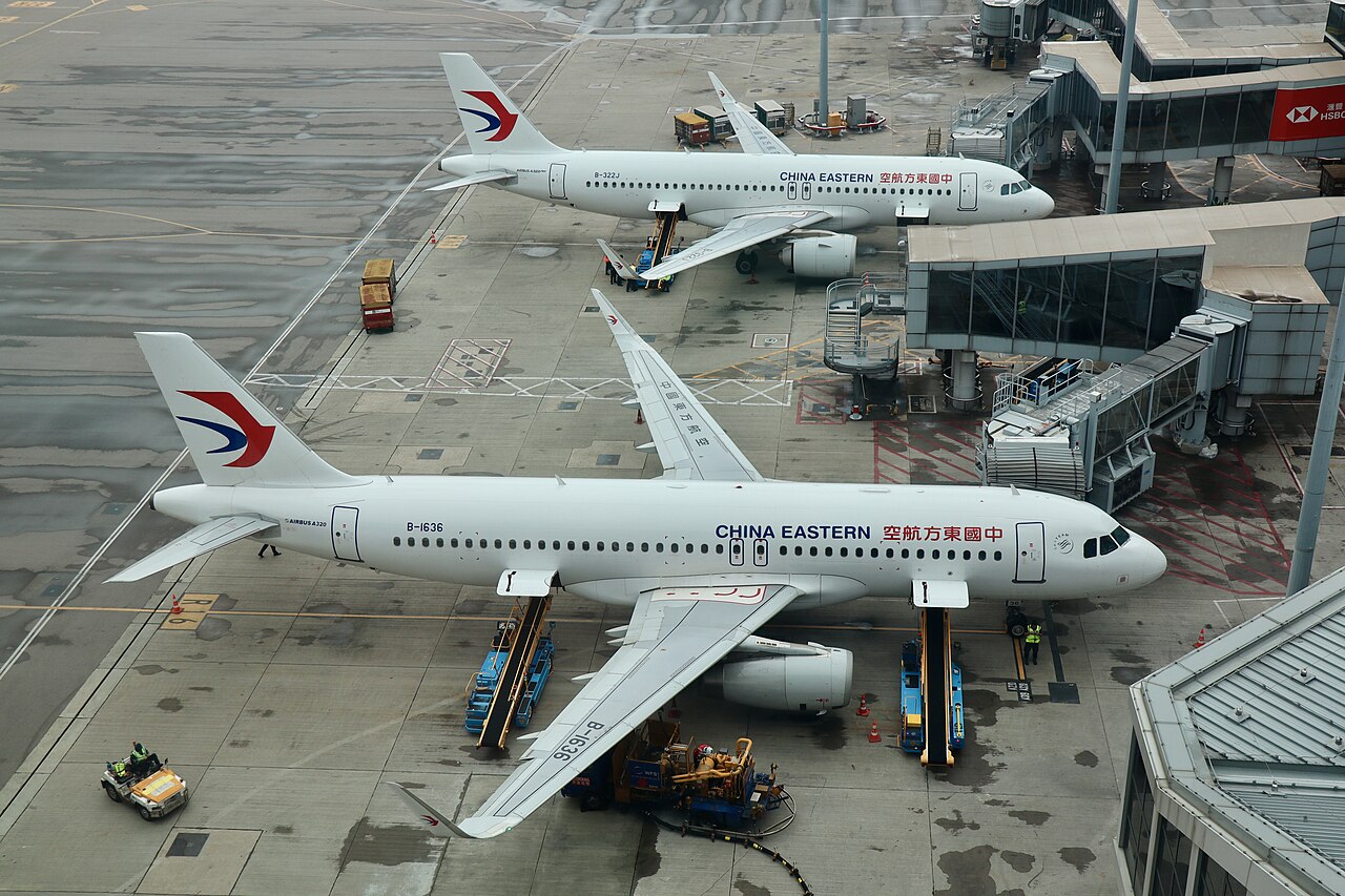 An overhead view of two China Eastern Airlines aeroplanes parked at airport gates on a wet tarmac.