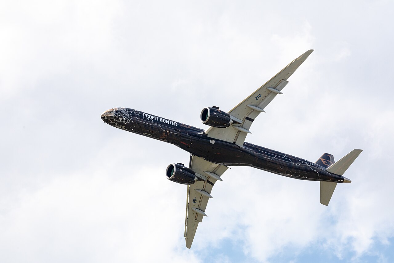 A dark blue and silver Embraer E195-E2 aircraft with the words 'Profit Hunter' visible on its body.