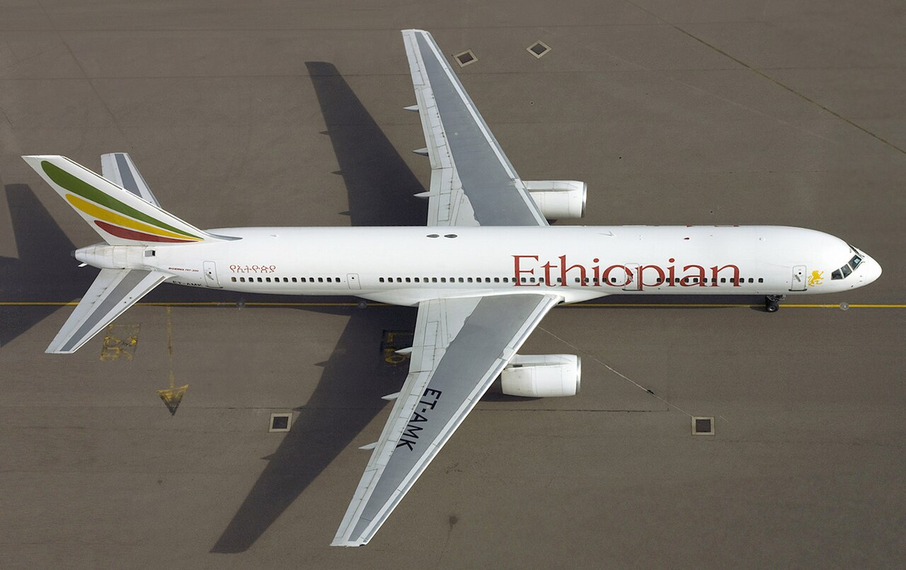 An Ethiopian Airlines' B757 seen from above, on top of a concrete runway. The Ethiopian Airlines' logo is written in red and the tail has the colours: green, yellow, and red. 