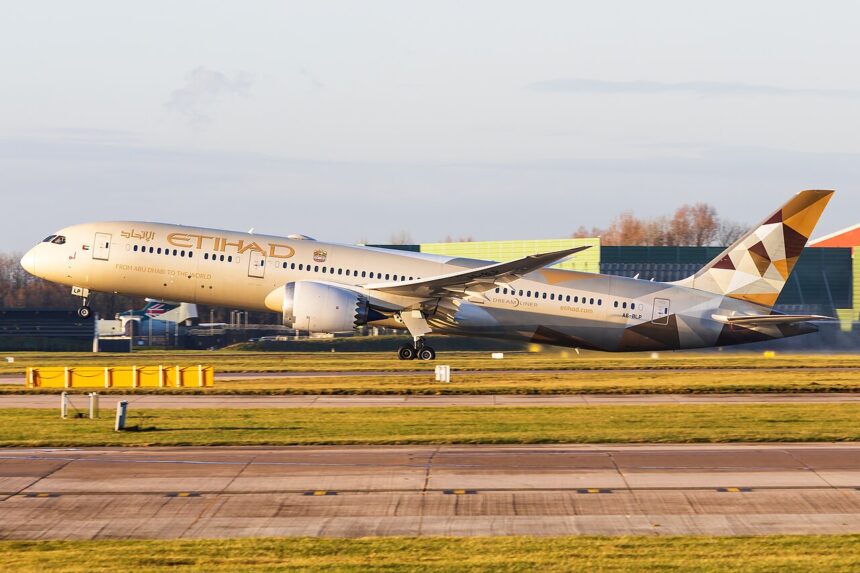 Etihad Airways B787 taking off at Manchester Airport in front of a grey sky, the sun shining on the aircraft.