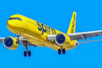 Spirit Airlines A321 flying under a blue sky. Yellow livery.