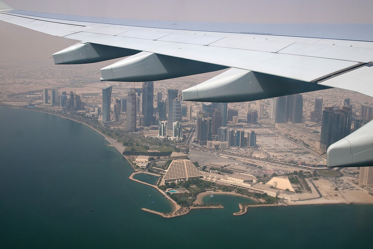 A view of Qatar's skyscrapers with a plane wing in the foreground.