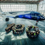Over 200 Lufthansa employees positioned in front of an Airbus A350, arranged to create the number 100
