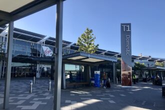 The entrance of Terminal One at Perth Airport, taken in 2022. It is a bright day with blue sky in the background.