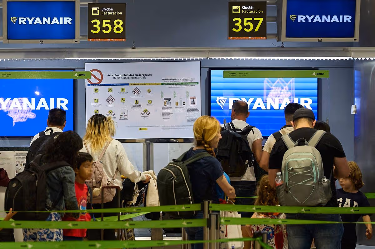 Image of people waiting to check in to Ryanair, people carrying luggage and weaving between green waiting chords.