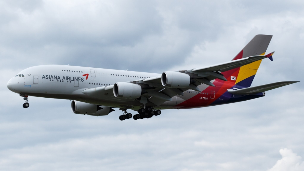 Asiana Airlines Airbus A380 in the air with pale blue skies and clouds surrounding it.