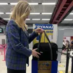 A person placing a bag into Ryanair's cabin bag service in an airport.