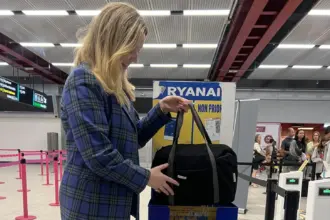 A person placing a bag into Ryanair's cabin bag service in an airport.