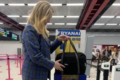 A person placing a bag into Ryanair's cabin bag service in an airport.