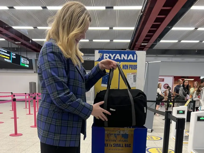 A person placing a bag into Ryanair's cabin bag service in an airport.