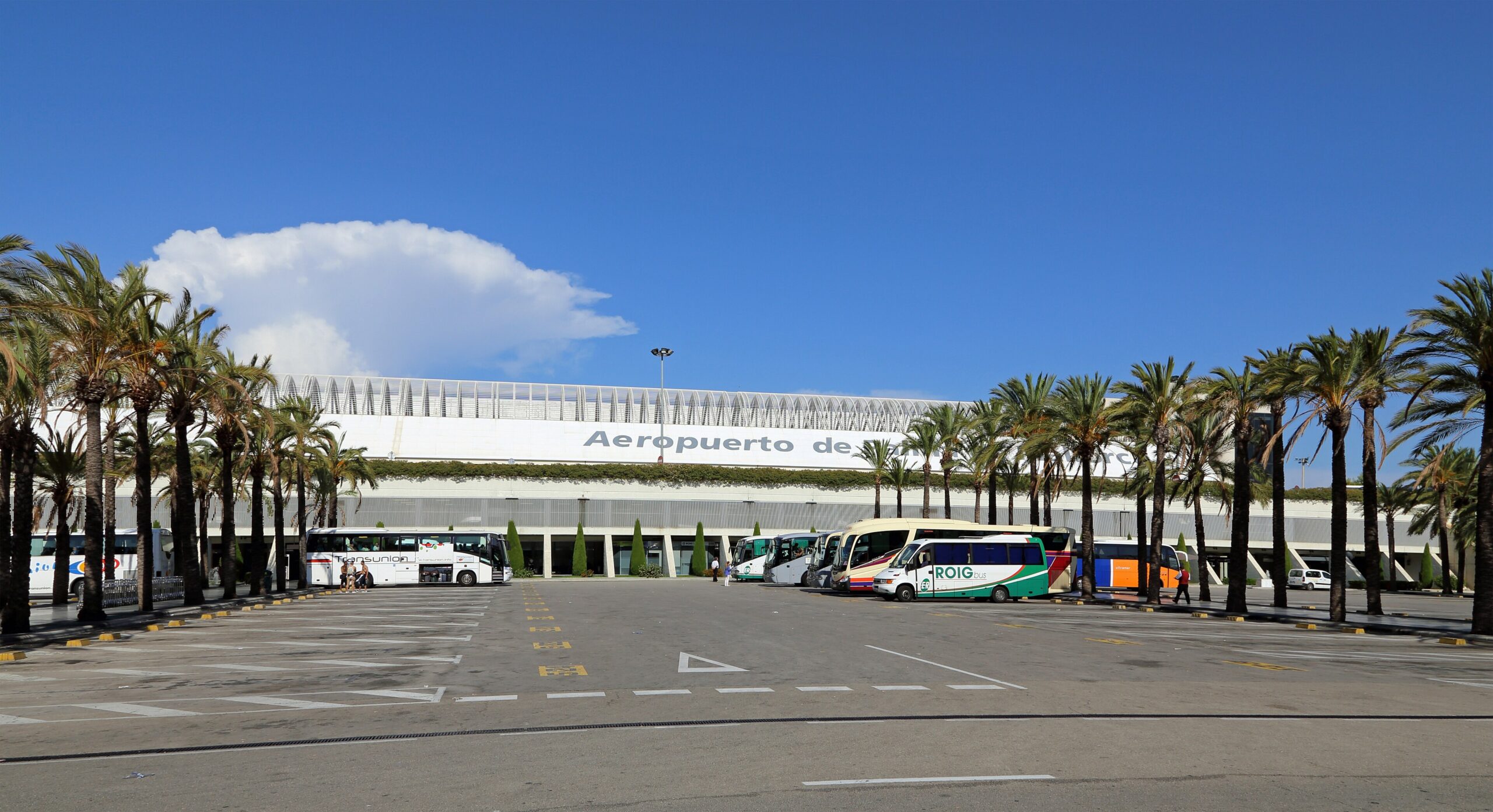 Palma de Mallorca Airport, Spain, exterior. Blue sky and palm trees in front of the building.