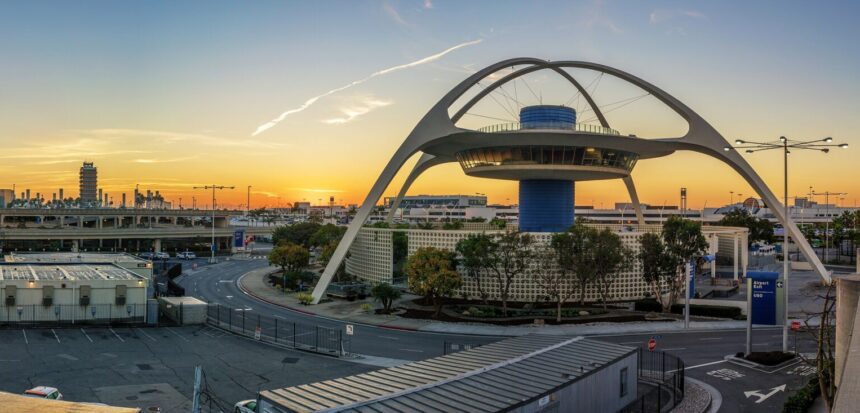 Sunrise over Los Angeles International Airport with aircraft silhouettes on the tarmac under an orange sky.