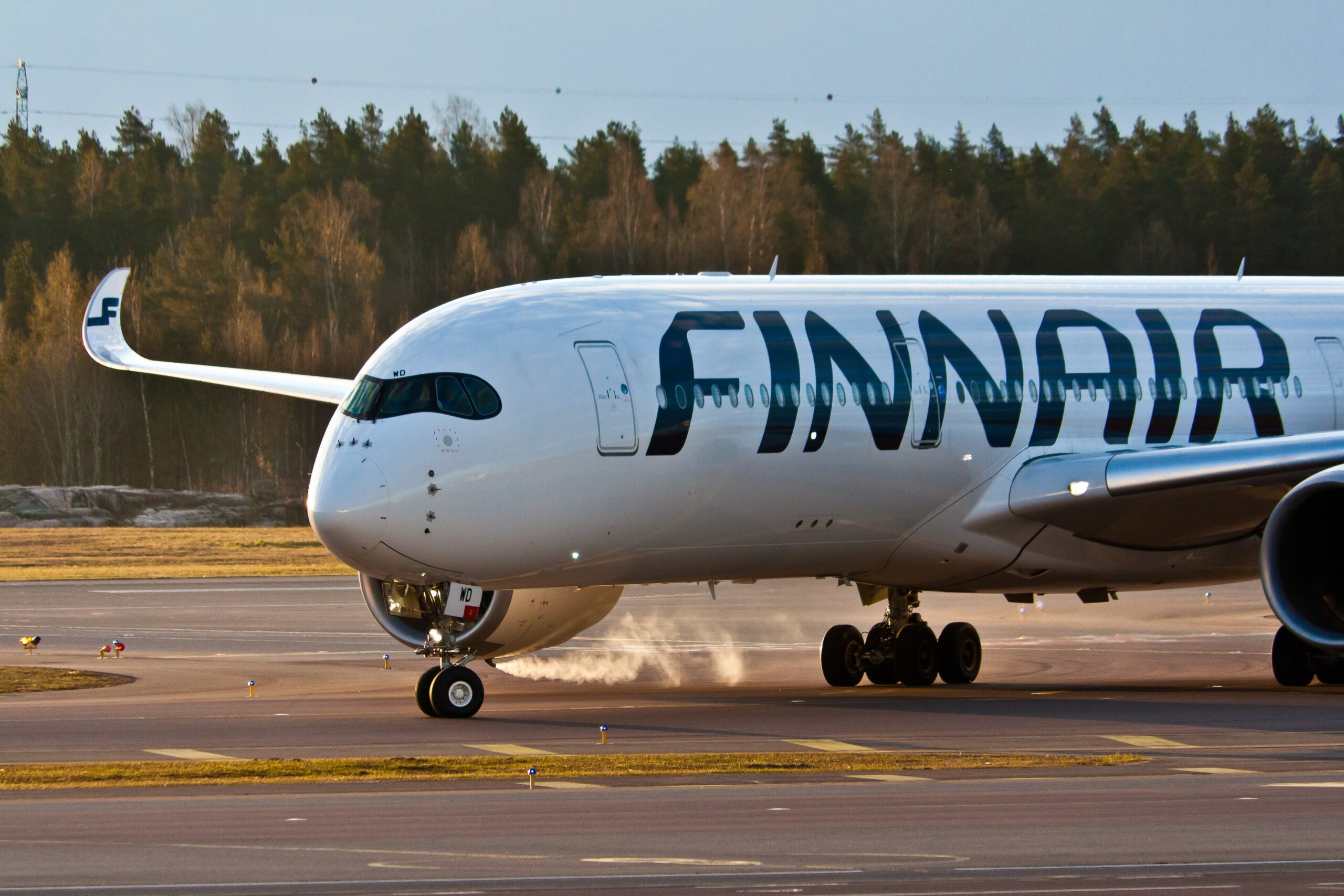 The front half of a Finnair A350 on the runway. Trees can be seen in the background