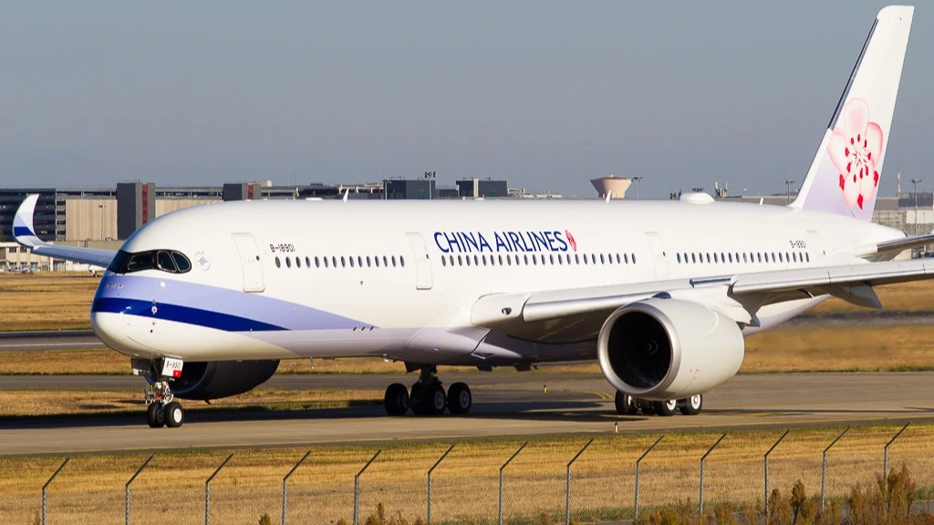 China Airlines aircraft with grey blue skies behind it and a building in the distance.