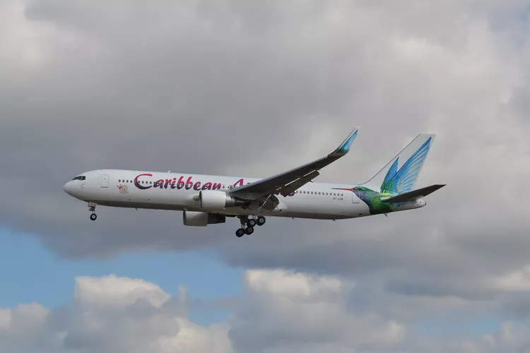 Caribbean Aircraft mid flight along grey skies and clouds.