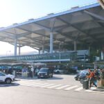 Exterior of Málaga airport. Cars parked outside, people with suitcases.