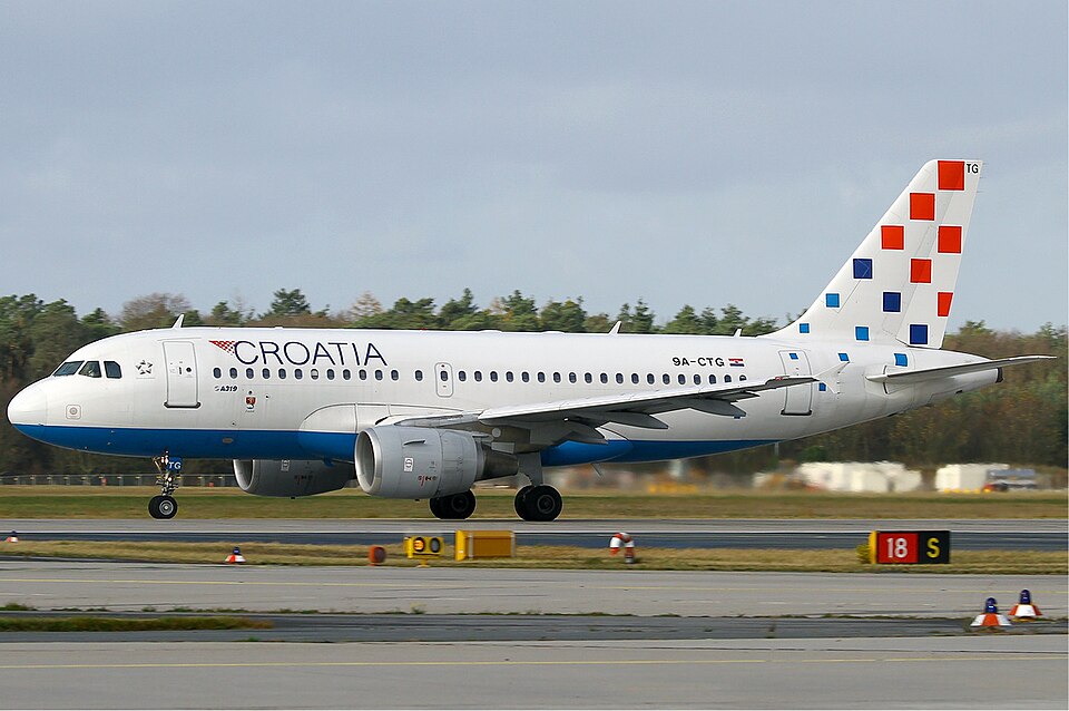 Croatia Airlines Airbus A319 aircraft on the runway before takeoff. White, red and blue livery. Grey sky in the background.