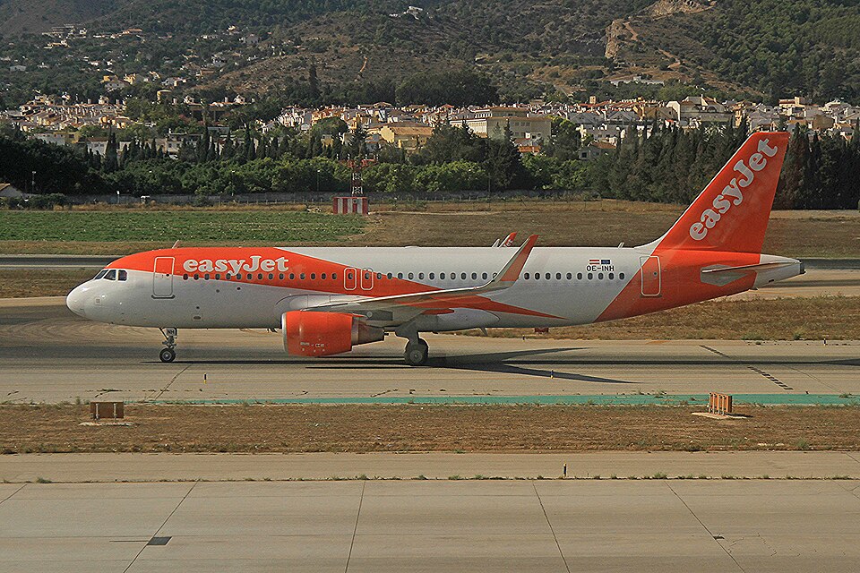 A side-profile photograph of an easy Jet Airbus A320-214 taxiing at Málaga–Costa del Sol Airport (AGP).