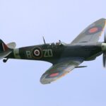 A high-angle shot of the Supermarine Spitfire MH434 in flight against a clear sky.