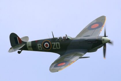 A high-angle shot of the Supermarine Spitfire MH434 in flight against a clear sky.