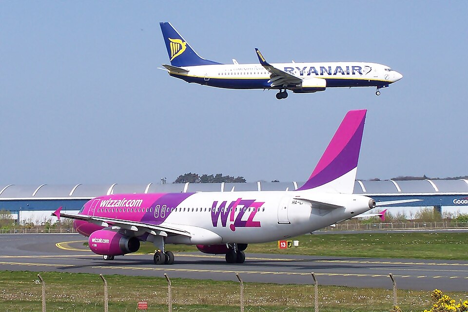 Ryanair 737 in the air, landing on runway 13 at Prestwick while Wizz A320 HA-LPM waits at the holding point.