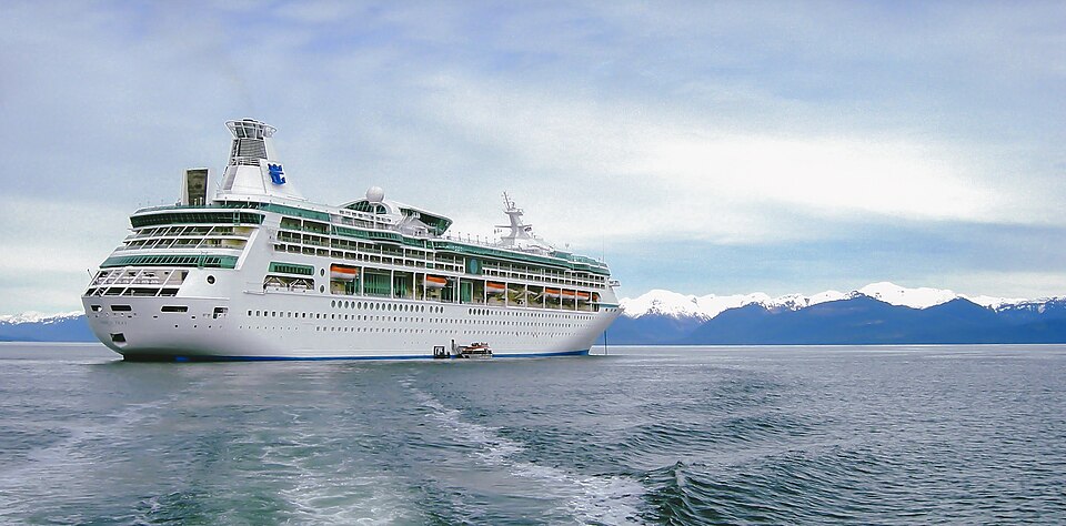 Royal Caribbean cruise ship traveling through a narrow Alaskan waterway.