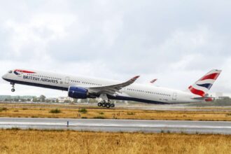 British Airway plane in the centre of the image taking off (facing towards the left). It has the British Airway flag logo on the tail. It is an overcast day in the background