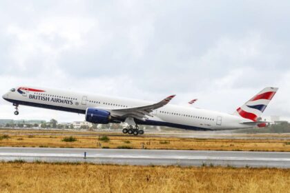 British Airway plane in the centre of the image taking off (facing towards the left). It has the British Airway flag logo on the tail. It is an overcast day in the background