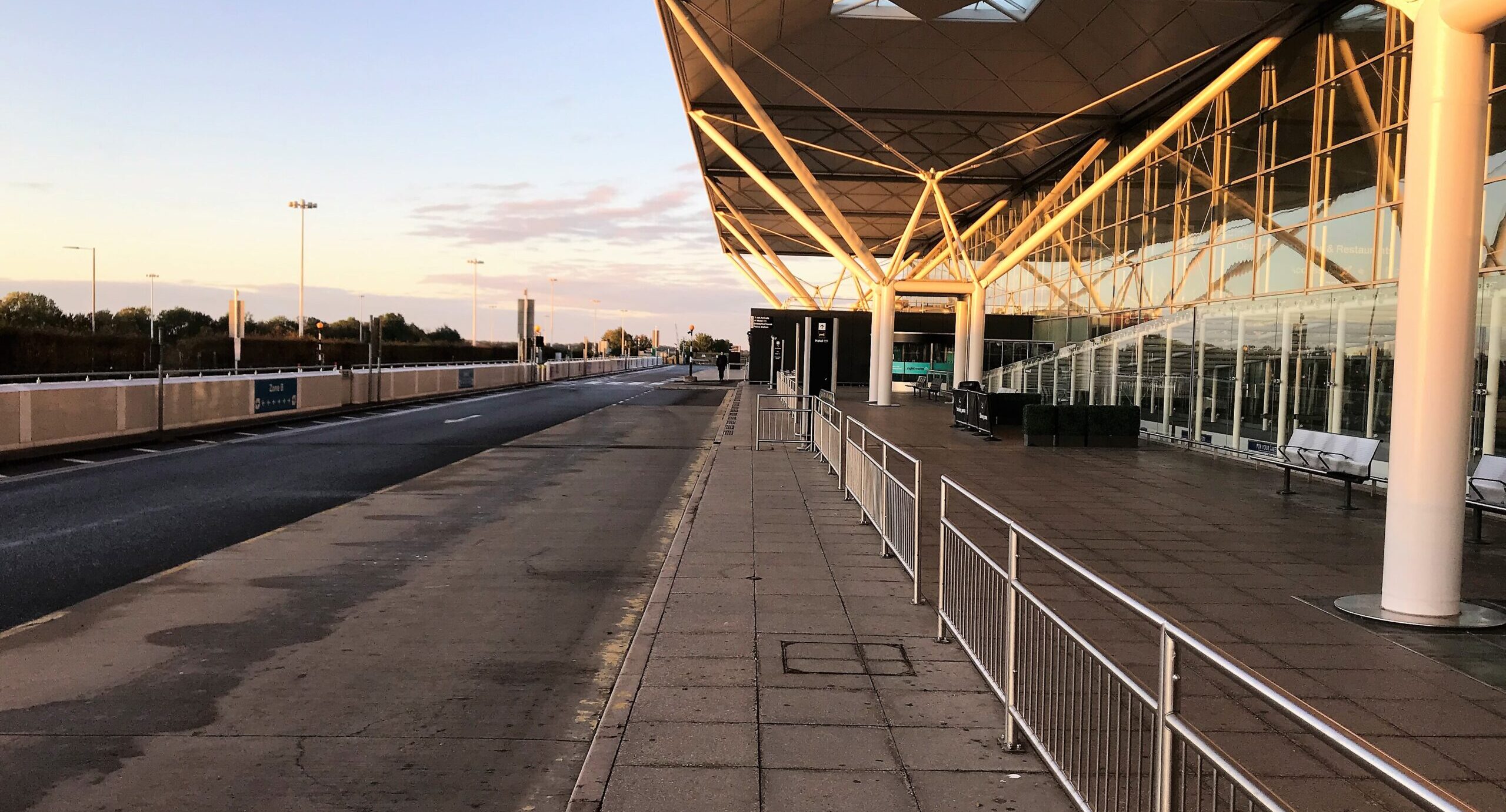 London Stansted Airport from the outside, railings and road visible.