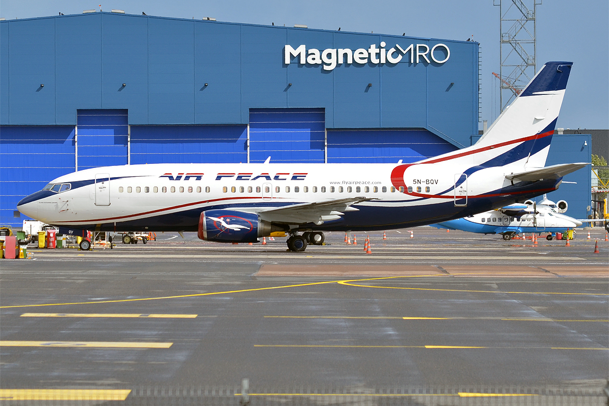 Air Peace, 5N-BQV, Boeing 737-33V, aircraft on the tarmac in front of a building that says "MagneticMRO". 