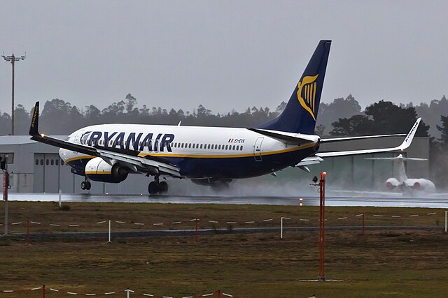 Ryanair Boeing 737 landing on runway of Santiago de Compostela airport. Grey sky in the background.
