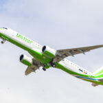 A green and white Binter Canarias plane soaring into the sky.