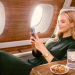Side view of an Emirates A380 passenger is enjoying Starlink Wi-Fi connectivity on her phone