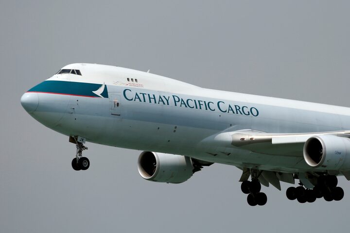 Cathay Pacific aircraft amid grey skies, flying through the sky.