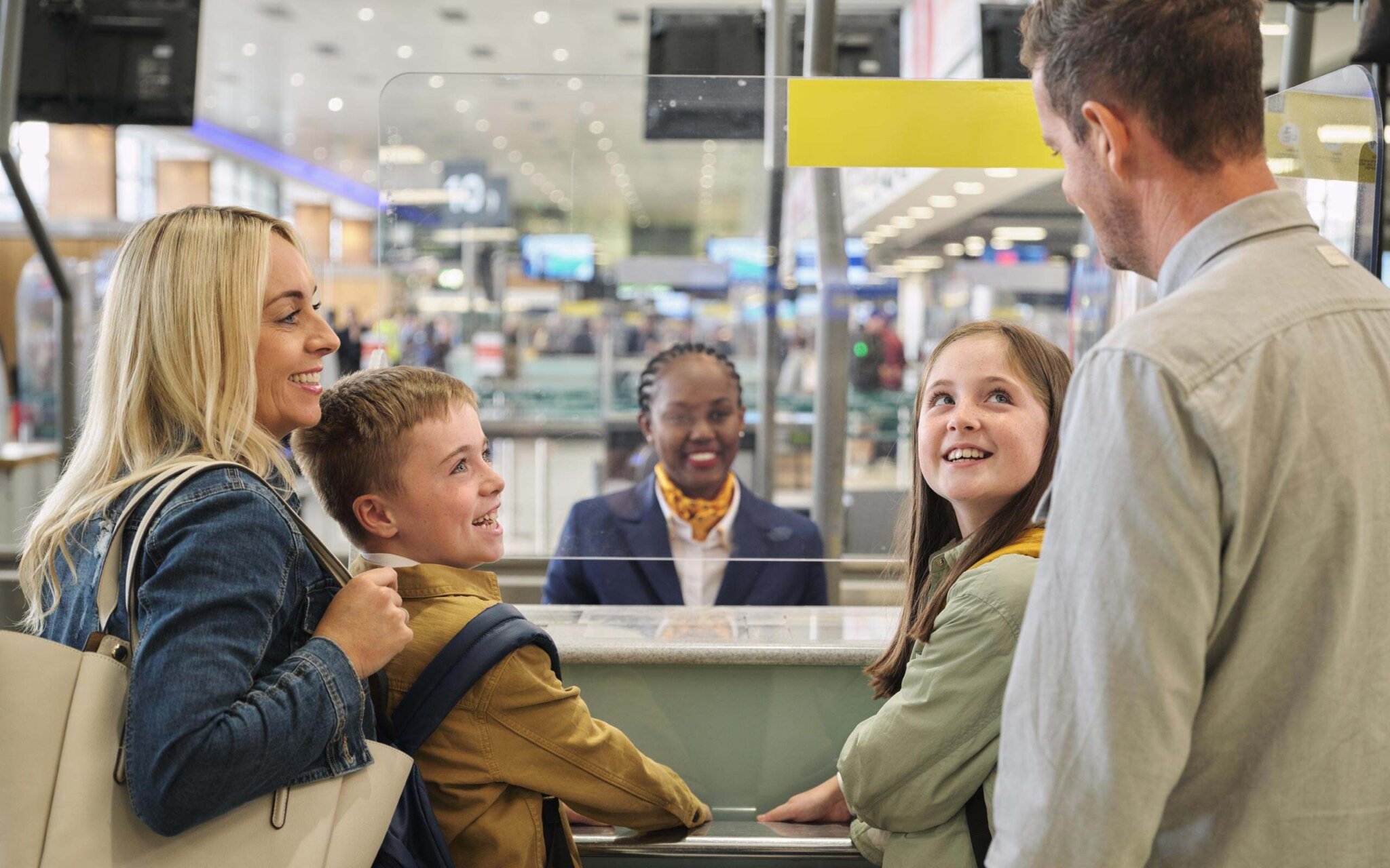 Image of a family talking to the check-in staff from behind a screen.