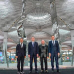Four key people standing in front of Hayri Karay's sculpture at its inauguration at iGA Istanbul Airport.