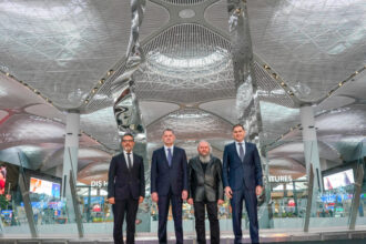 Four key people standing in front of Hayri Karay's sculpture at its inauguration at iGA Istanbul Airport.