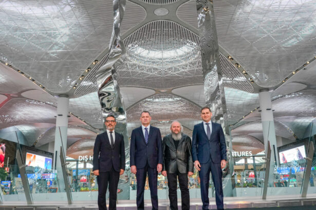 Four key people standing in front of Hayri Karay's sculpture at its inauguration at iGA Istanbul Airport.