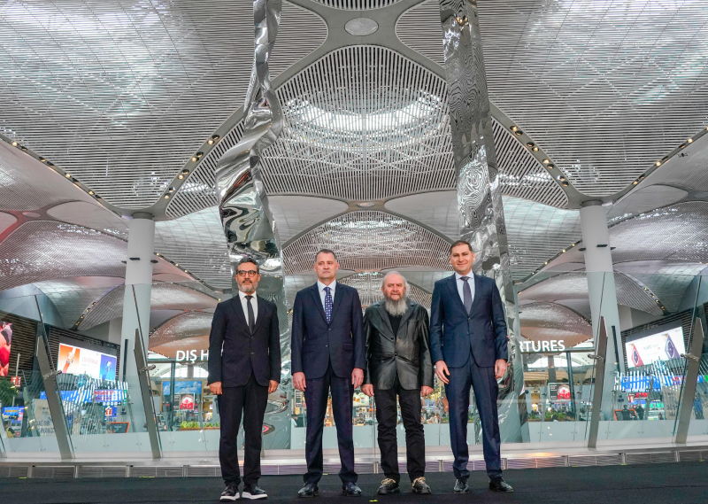 Four key people standing in front of Hayri Karay's sculpture at its inauguration at iGA Istanbul Airport.