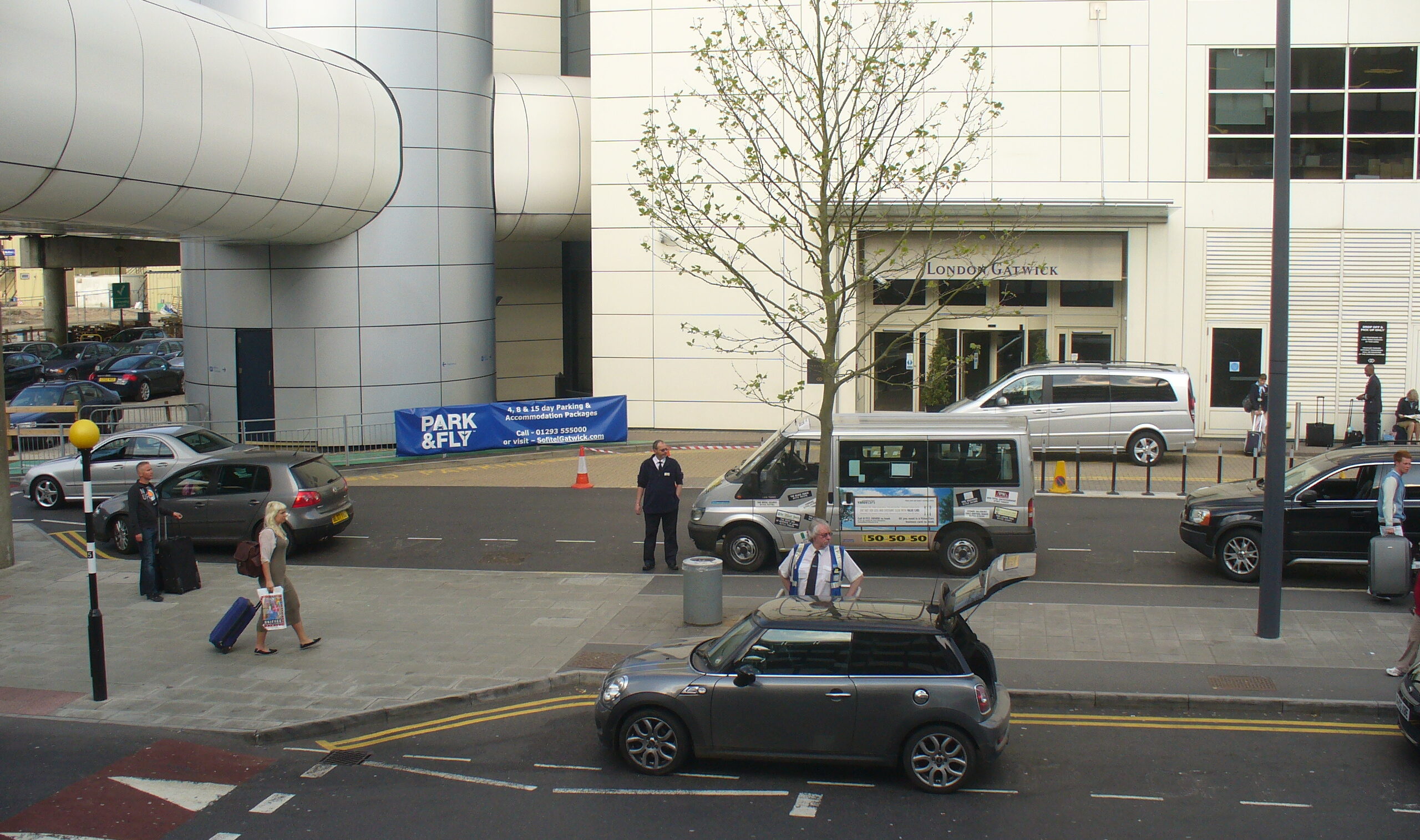 London Gatwick Airport, cars on roads, pedestrians crossing the street. 
