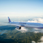 A China Airlines plane flying amid clouds and blue skies with a landscape of greenery underneath.