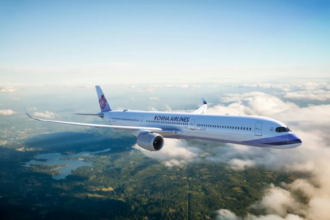 A China Airlines plane flying amid clouds and blue skies with a landscape of greenery underneath.