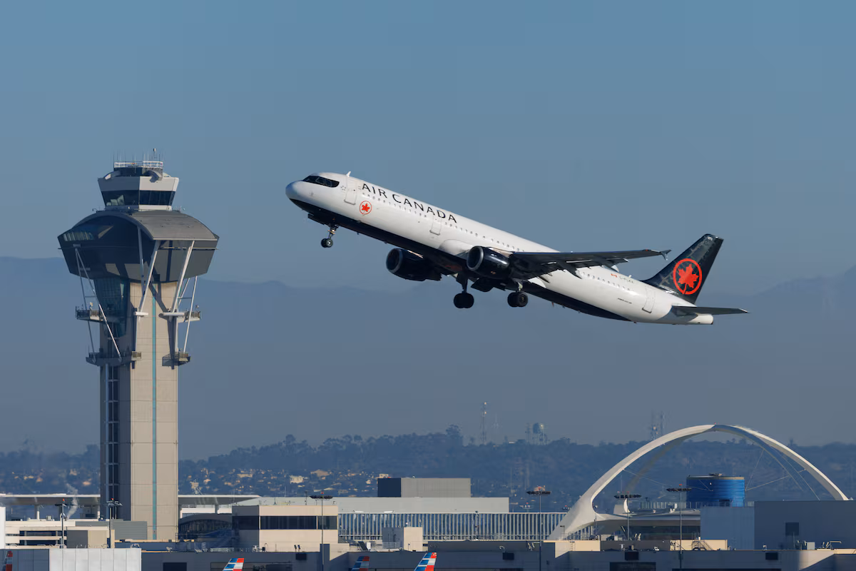 An Air Canada aircraft taking off at Los Angeles International Airport, buildings in the background.