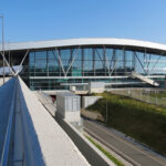 Exterior of Santiago de Compostela airport. Bushes on the right side, blue sky in the background.