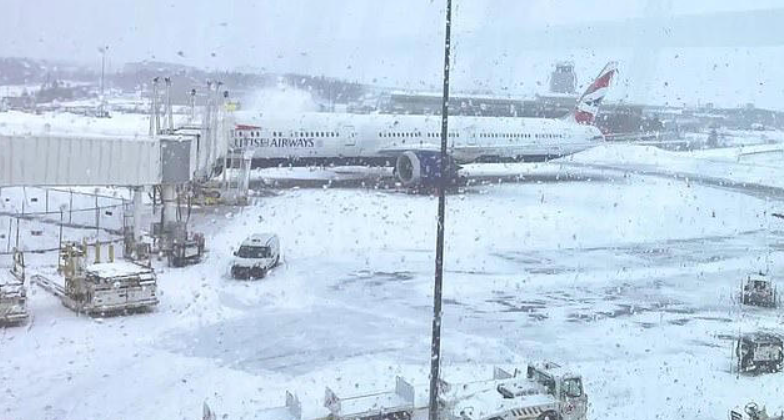 An airport covered in snow and ice with a large British Airways jetliner sitting outside