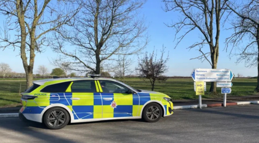 A police car sitting beside a stretch of grass with trees in the background