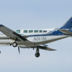 A small blue and white plane flying in a clear skty