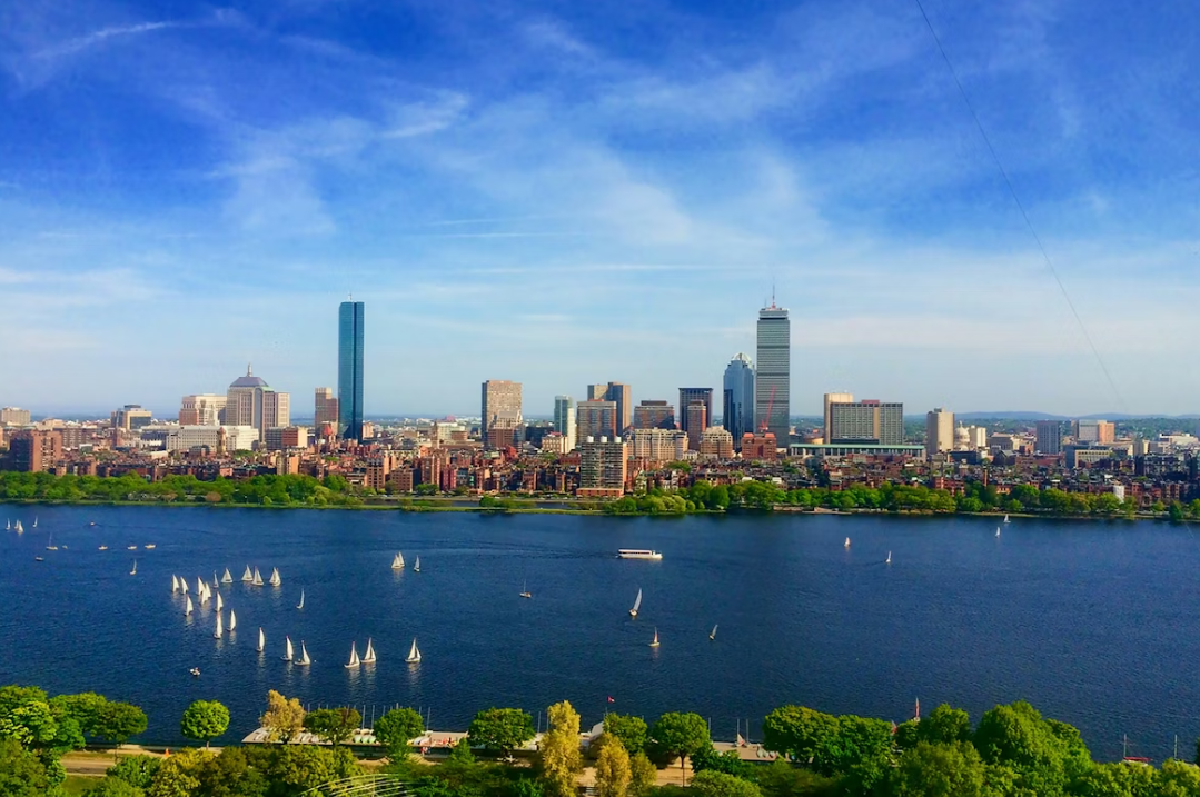 A large body of water with boats, in front of a cityscape at daytime