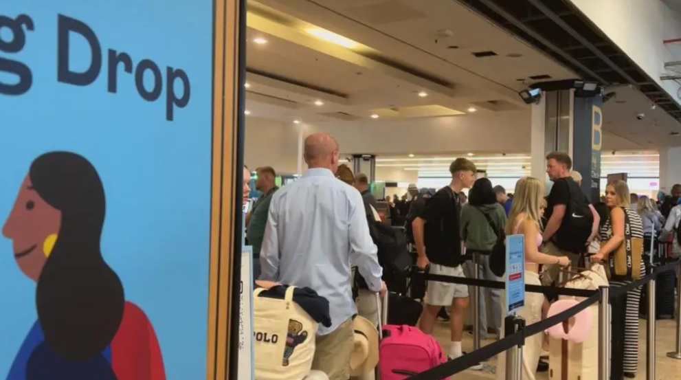 People queuing in line behind black barriers